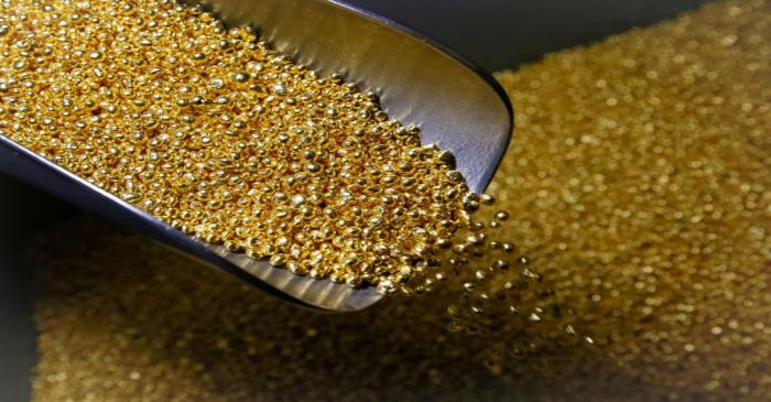 FILE PHOTO: An employee takes granules of 99.99% pure gold at the Krastsvetmet non-ferrous