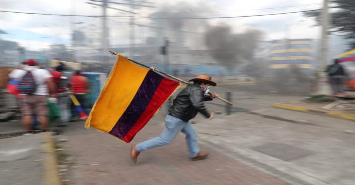 FILE PHOTO: A demonstrator runs while holding an Ecuadorian flag during a protest against