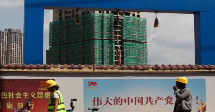 Workers walk past a construction site of residential buildings by property developer Country