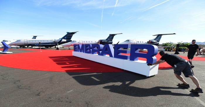 Workers set up at the Embraer booth prior to the opening of the National Business Aviation