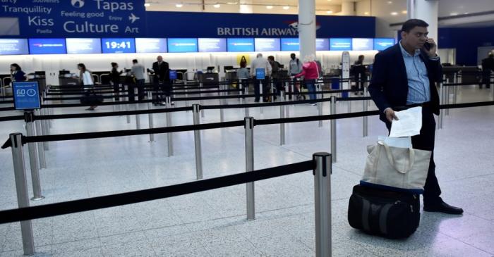 A man waits with his luggage at Gatwick Airport in southern England