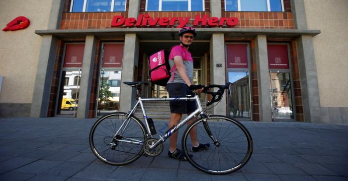 A Foodora delivery cyclist poses in front of Delivery Hero headquarters in Berlin