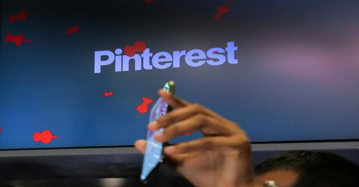 A guest hold up a phone during the Pinterest Inc. IPO on the floor of the NYSE in New York