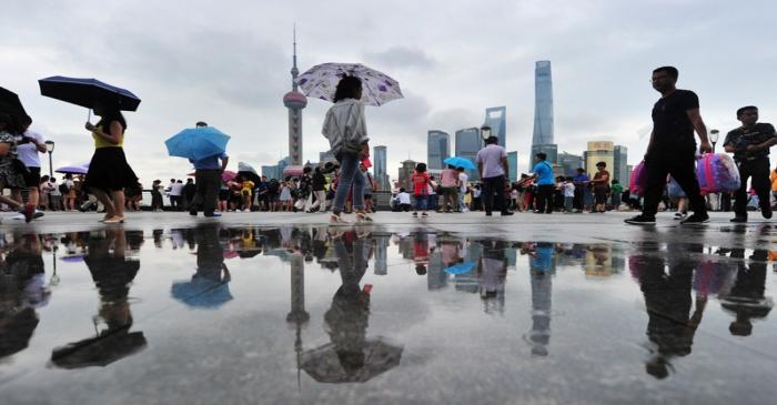 People walk on the bund amid drizzle near the financial district of Pudong in Shanghai