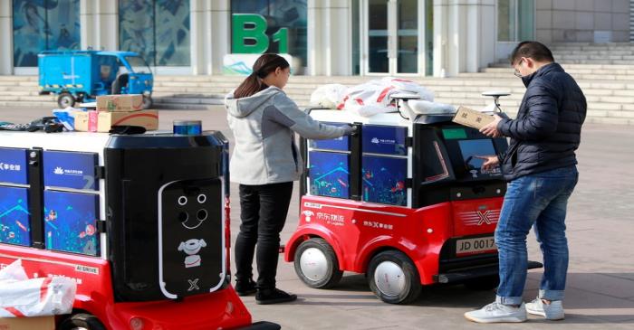 FILE PHOTO: People retrieve their parcels from a JD.com driverless delivery robot a day after