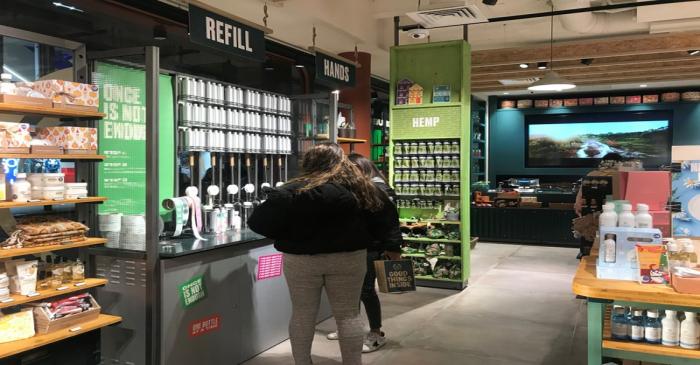Customers look at a station for refilling shower gel at a Body Shop store on Bond Street in