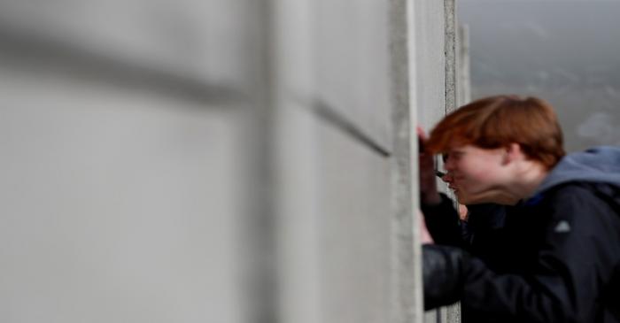 FILE PHOTO: Visitors peers through segments of Wall at the Berlin Wall memorial on Bernauer