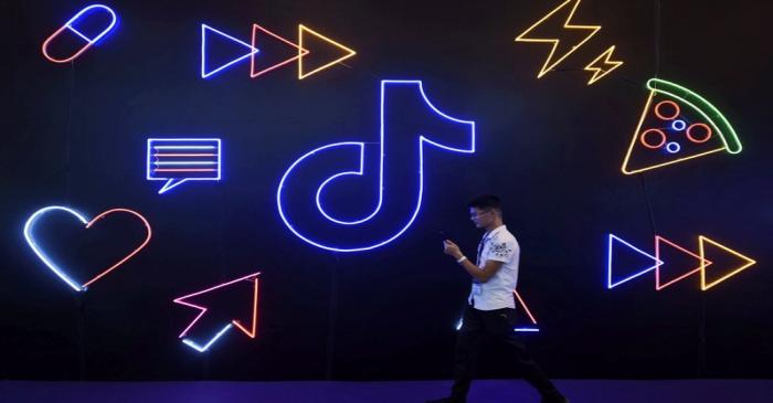 FILE PHOTO: Man walks past a sign of ByteDance's app TikTok, known locally as Douyin, at an