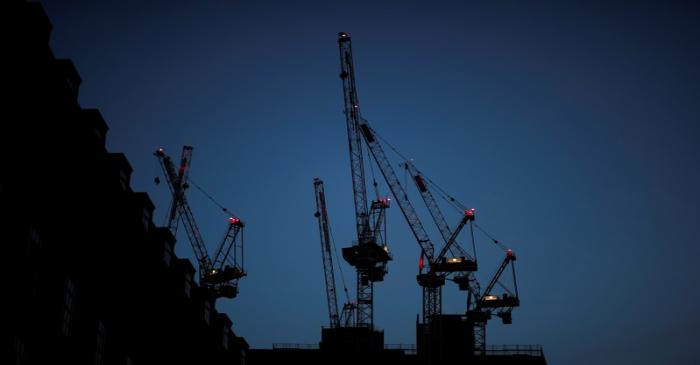 Construction cranes are seen on a building site at sunrise in central London