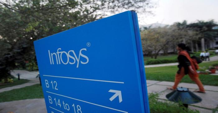 FILE PHOTO: An employee walks past a signage board in the Infosys campus at the Electronics