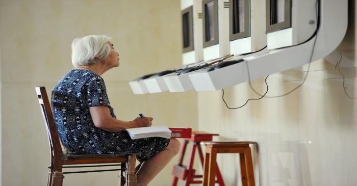 Woman sits in front of terminals showing stock information at a brokerage house in Jinhua