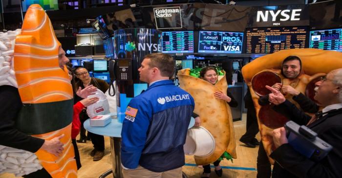 FILE PHOTO: People dressed in food-themed costumes walk on the floor of the New York Stock