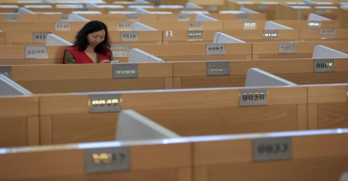 A trader checks her phone on the trading floor at the Shanghai Stock Exchange in Lujiazui