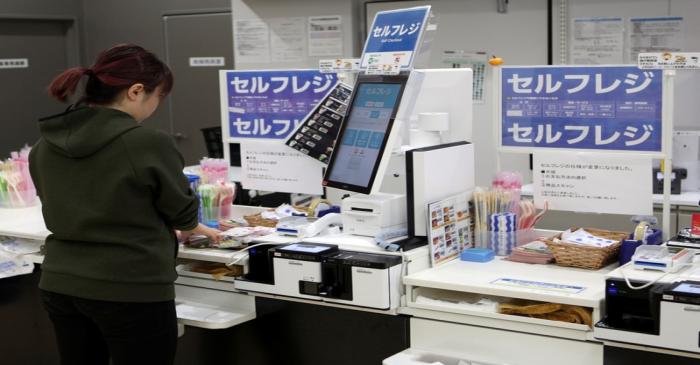 A shopper checks out at an unmanned cash register with using her mobile phone at convenience