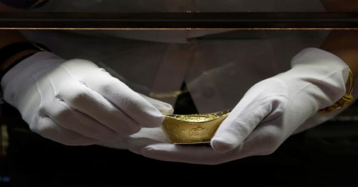 A sales assistant takes out a gold ornament for a customer at Caibai Jewelry store in Beijing