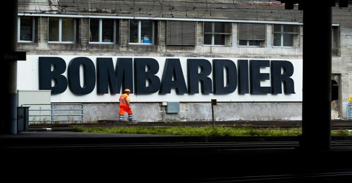 A worker walks in front of a Bombardier advertising board at the SBB CFF Swiss railway train