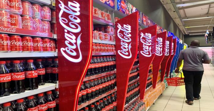 A man walks past shelves of Coca-Cola bottles and cans at a Shoprite store inside Palms
