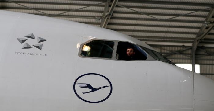 A technician looks out of the cockpit of a Lufthansa Airbus A330-300 aircraft in a maintenance