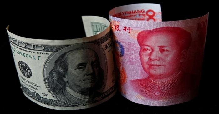 FILE PHOTO: A 100 yuan banknote is placed next to a $100 banknote in this picture illustration