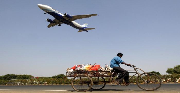 An IndiGo Airlines aircraft prepares to land as a man paddles his cycle rickshaw in Ahmedabad