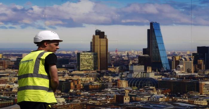 A worker walks past a picture of the London skyline outside the sales office of a property