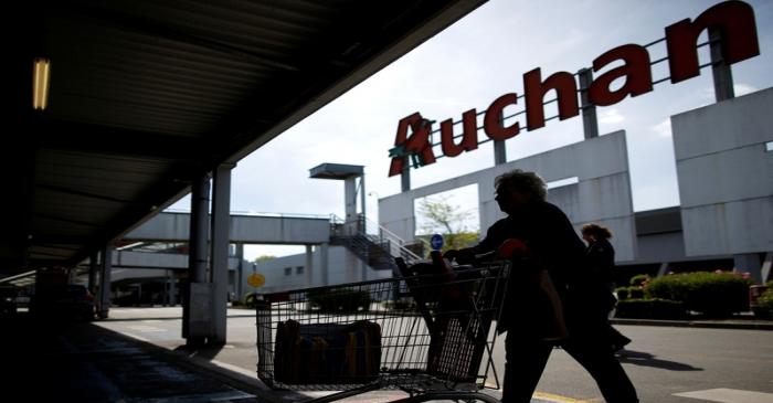 FILE PHOTO: A customer walks with a shopping trolley at the entrance of an Auchan Hypermarket