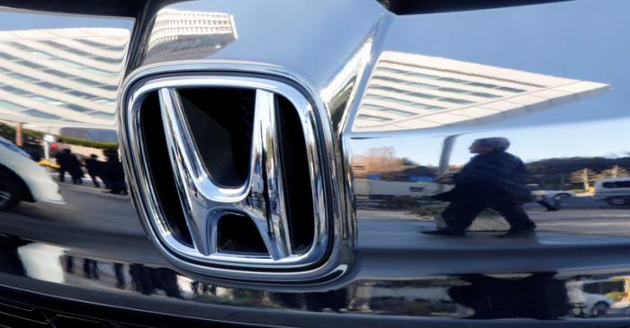 People are reflected on a Honda Motor car outside the company's headquarters in Tokyo