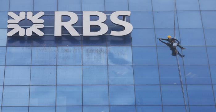 FILE PHOTO: Worker cleans the glass exterior next to the logo of RBS (Royal Bank of Scotland)