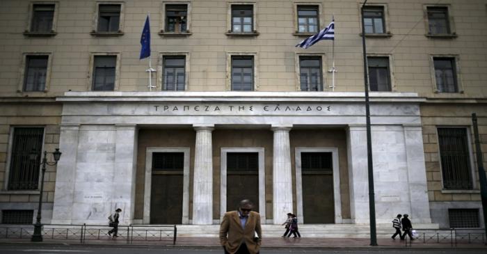 People make their way next to the headquarters of Bank of Greece in central Athens