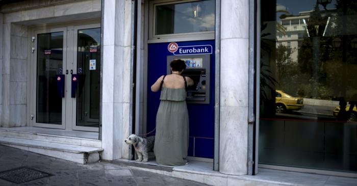 FILE PHOTO: Woman uses a Eurobank ATM in Athens