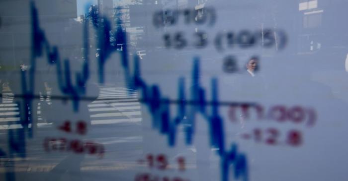 A man is reflected on an electronic board showing a graph analyzing recent change of Nikkei