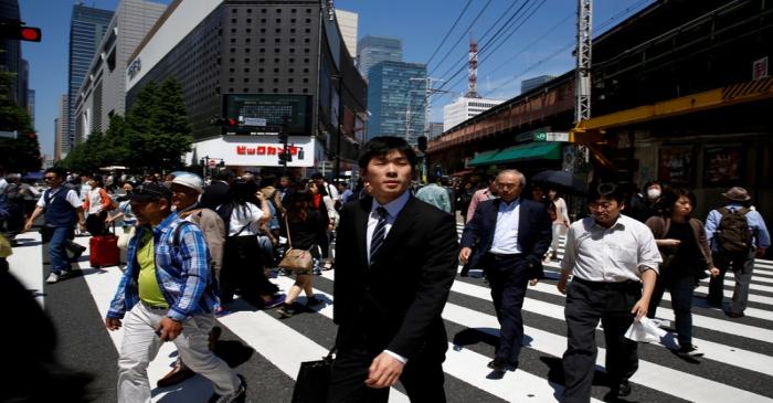 FILE PHOTO: People cross a junction in front of an electronics retailer in a business district