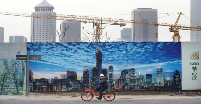 A man cycles outside the construction sites in Beijing's central business area