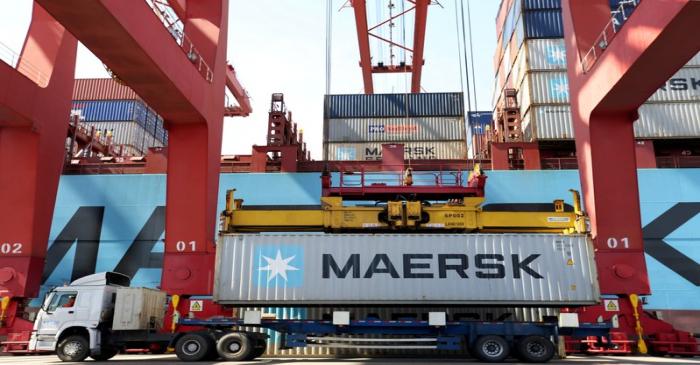 FILE PHOTO: Truck transports a Maersk shipping container by a cargo ship at a port in Qingdao
