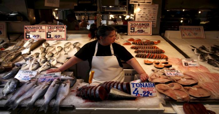 A fishmonger waits for customers in a local market in central Athens