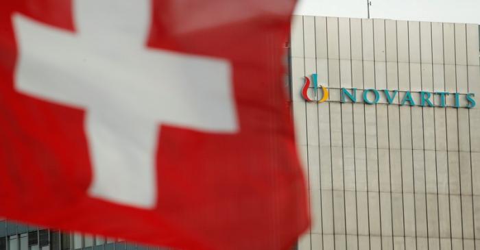 FILE PHOTO: Switzerland's national flag flies in front of the logo of Swiss drugmaker Novartis