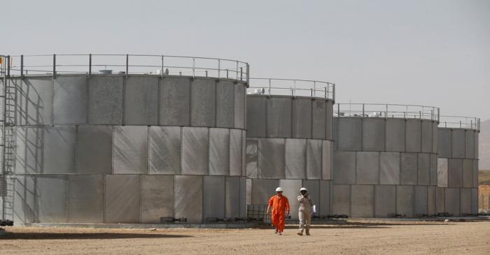 FILE PHOTO: Workers walk past storage tanks at Tullow Oil's Ngamia 8 drilling site in Lokichar