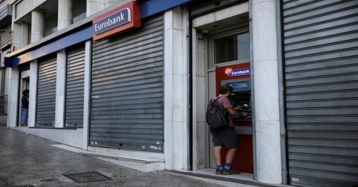 FILE PHOTO: A man uses an ATM outside a Eurobank branch in Athens