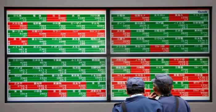 FILE PHOTO: Men look at stock quotation boards outside a brokerage in Tokyo