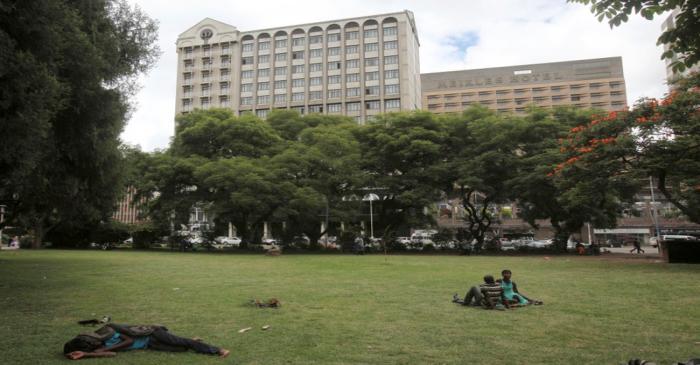 FILE PHOTO: Zimbabweans rest at a park outside Meikles Hotel in central in Harare