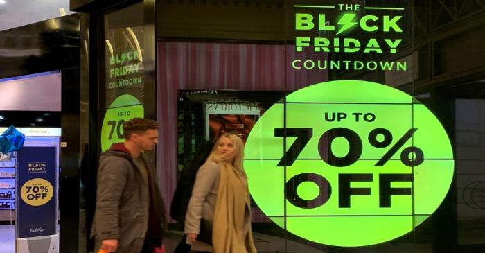 People walk past a sign advertising Black Friday offers at a perfume store in Manchester