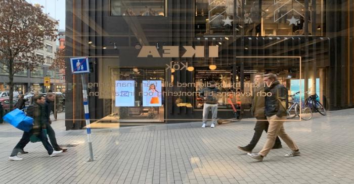 People in the street are seen from inside an IKEA kitchen showroom and planning studio in the