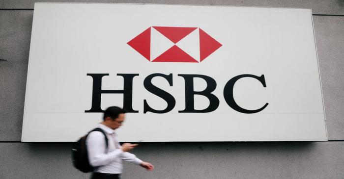 A man walks past a logo of HSBC at its headquarters in Kuala Lumpur