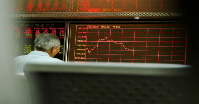 A man sits in front of a board showing market information at a securities brokerage house in