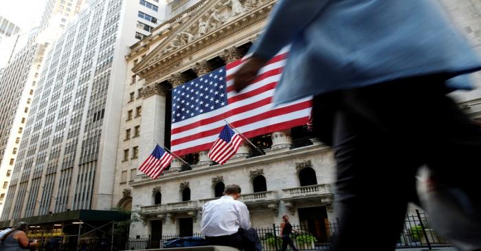 FILE PHOTO: People sit outside the NYSE during the morning commute