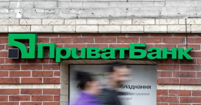 People walk past a branch of PrivatBank, the country's biggest lender, in Kiev