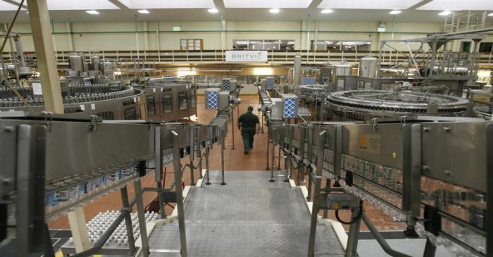 A worker walks through machinery at drinks company  Britvic's bottling plant in London