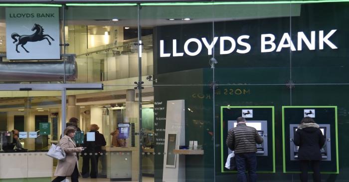 Customers use ATMs at a branch of Lloyds Bank in London
