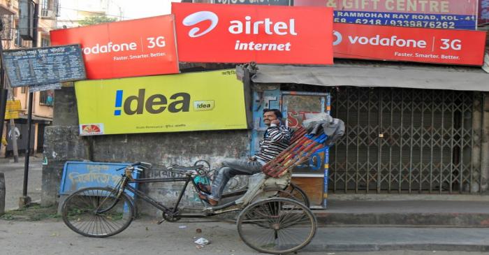 FILE PHOTO:  A rickshaw puller speaks on his mobile phone as he waits for customer in front of