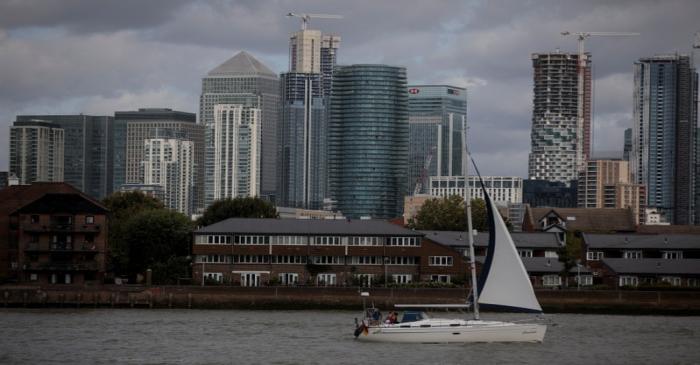 A sailing boat moves past the Canary Wharf financial district on the River Thames in London